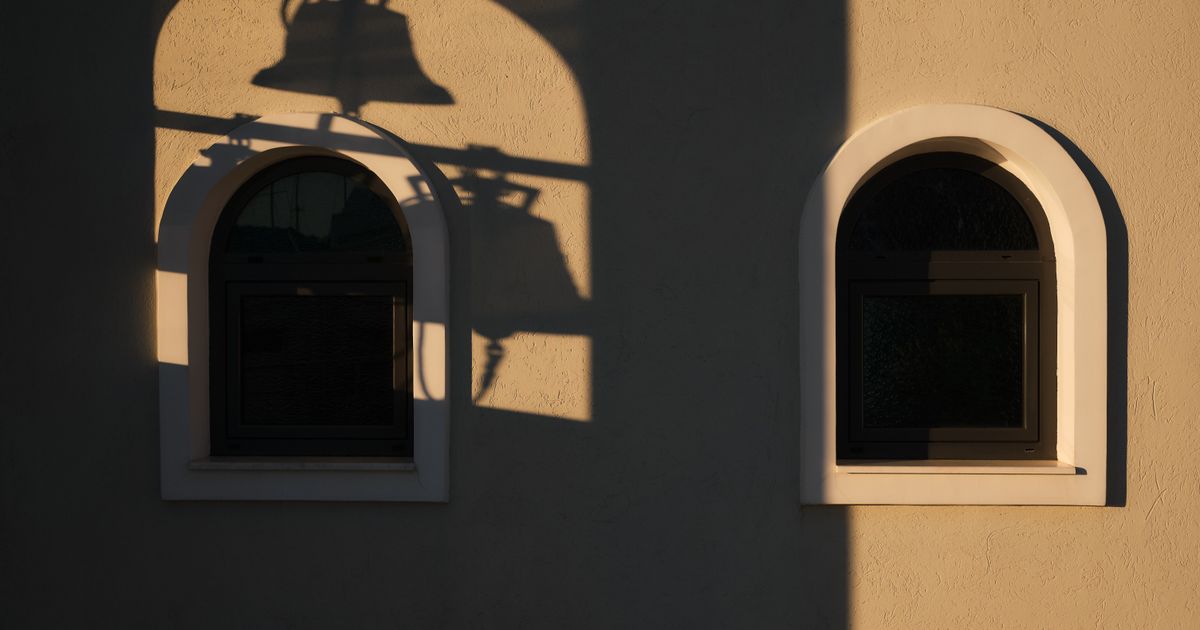 Arched windows and the shadow of a bell on a wall
